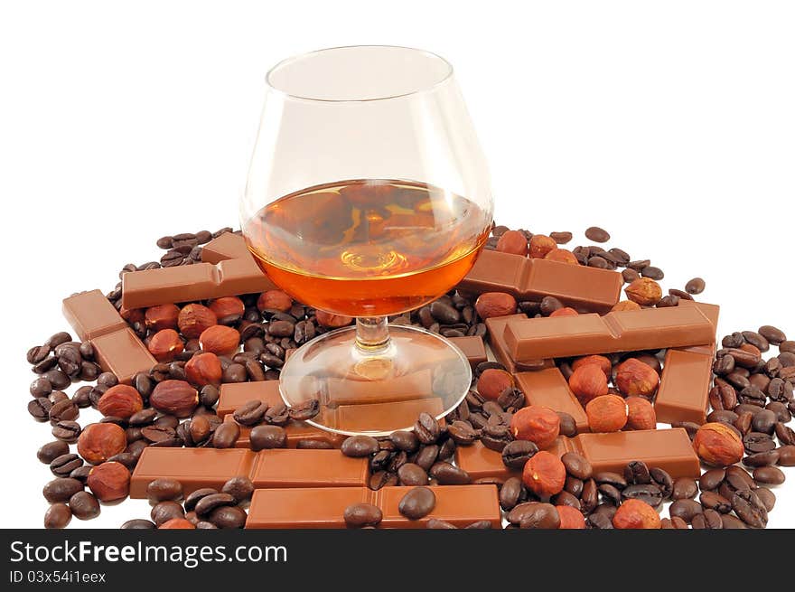 Glass with cognac with chocolate, coffee and nuts on a white background