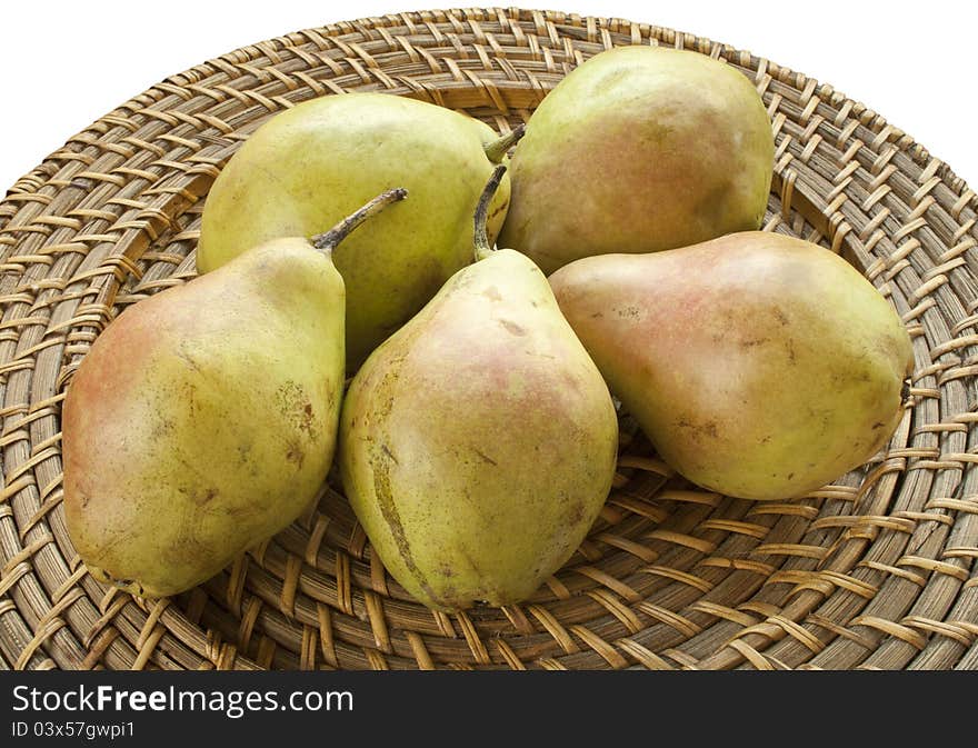 Fresh pears on wicker plate on white