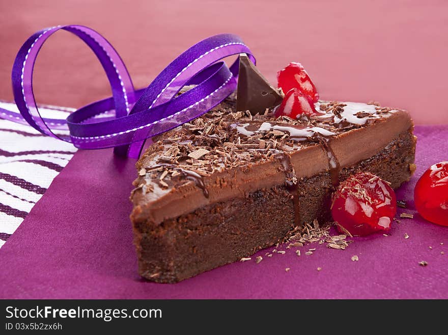 Delicious chocolate cake on purple background. Culinary sweet desert still life. Delicious chocolate cake on purple background. Culinary sweet desert still life.