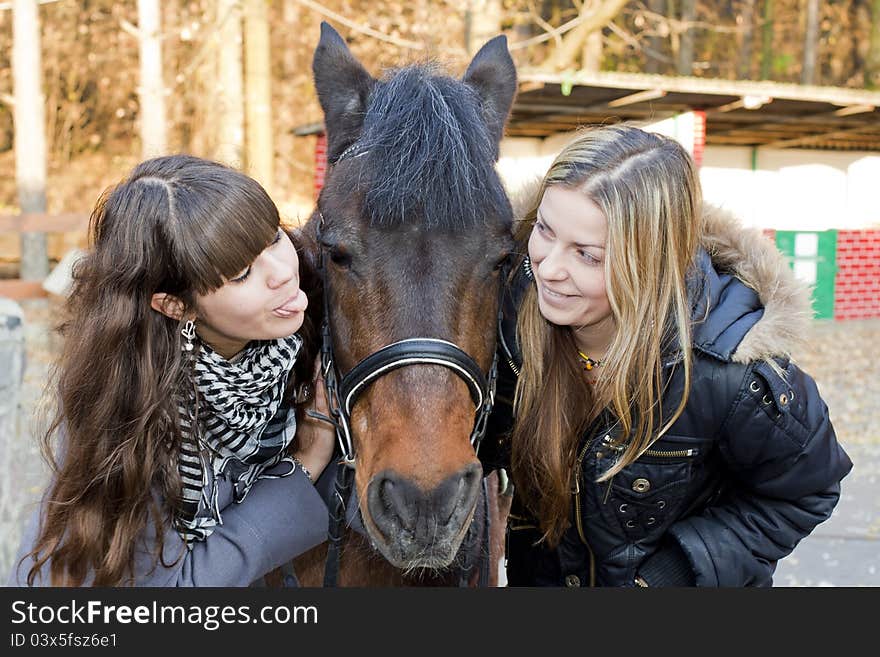 Two happy girls playing with a horse and smiling. Two happy girls playing with a horse and smiling