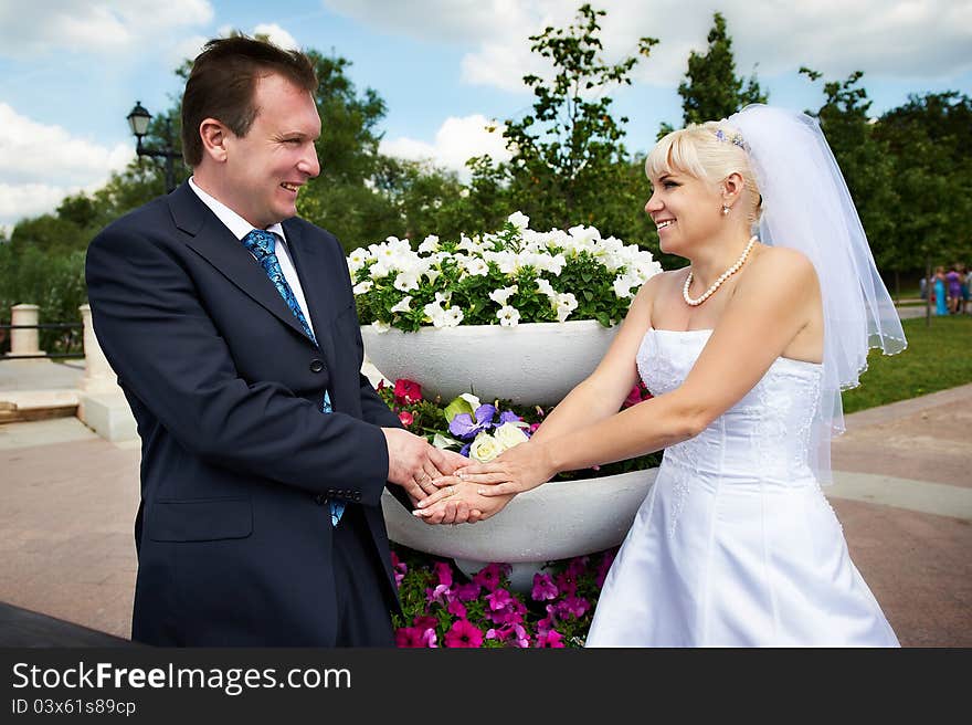 Happy groom and happy bride near flowers bed