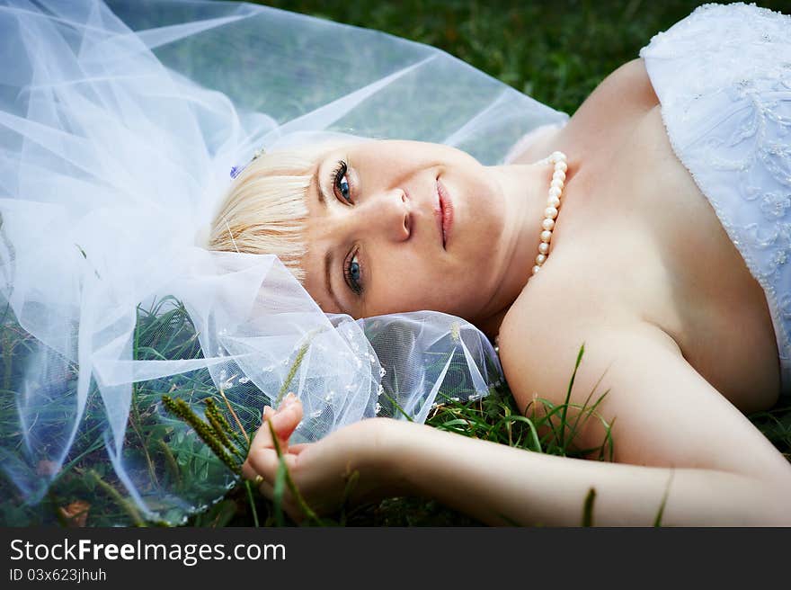 Portrait beautiful bride lying on grass in wedding day