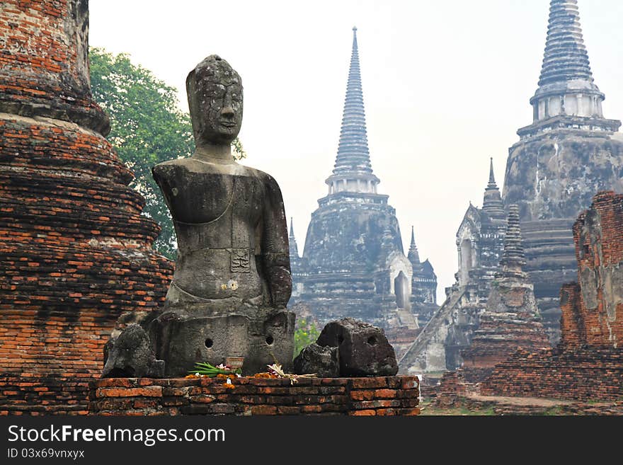 Headless and armless Buddha image sitting in front of stupa in Ayutthaya, Thailand. Headless and armless Buddha image sitting in front of stupa in Ayutthaya, Thailand