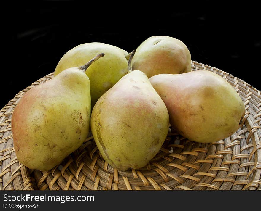 Fresh pears on wicker plate on black. Fresh pears on wicker plate on black