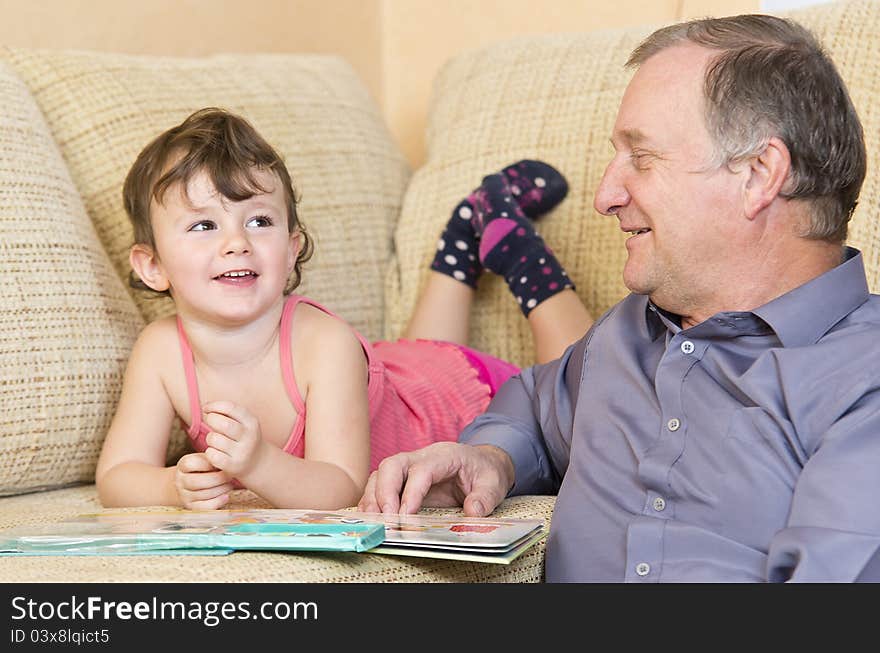 Three years old girl reading and playing with her grandfather. Three years old girl reading and playing with her grandfather.