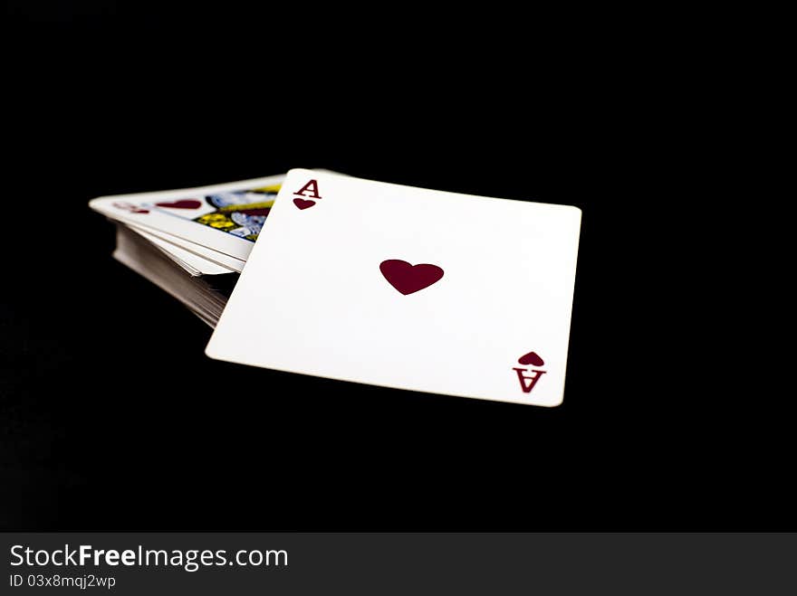 A pack of playing cards with the ace of hearts to top;black background. A pack of playing cards with the ace of hearts to top;black background