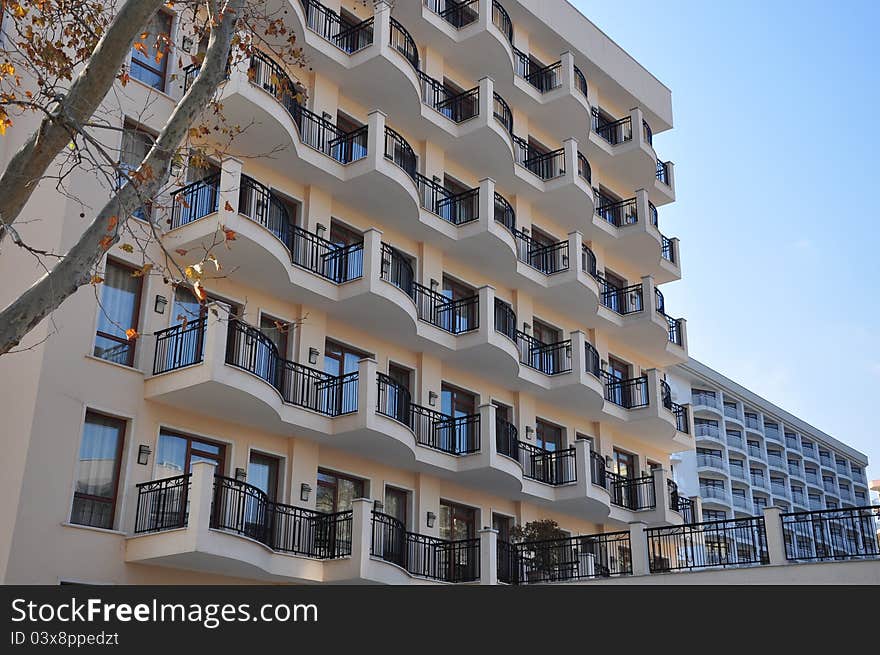 Windows facade and balconies on modern buildings and tree branch. Windows facade and balconies on modern buildings and tree branch