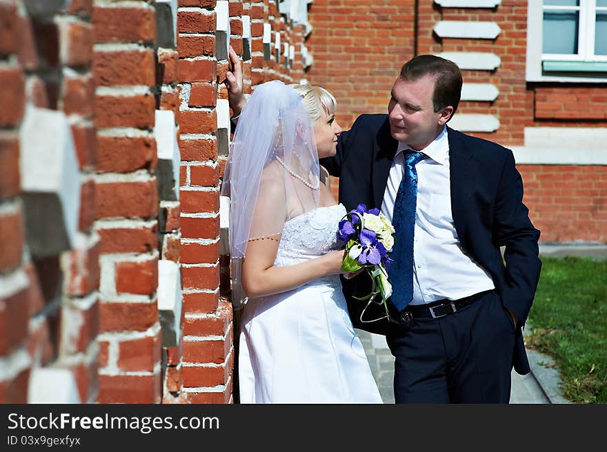 Happy bride and groom near red brick wall