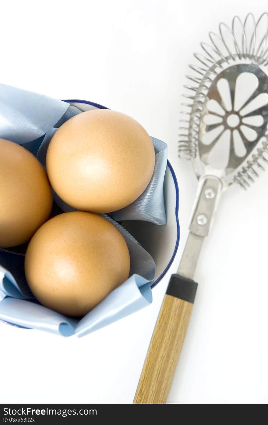 Eggs with kitchenware on white background