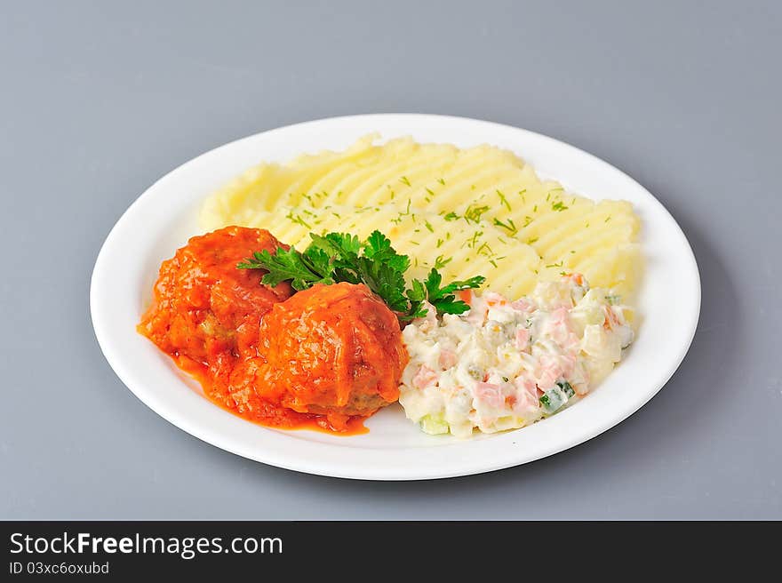 Meatball in tomato sauce with mashed potato and olivie salad. Meatball in tomato sauce with mashed potato and olivie salad