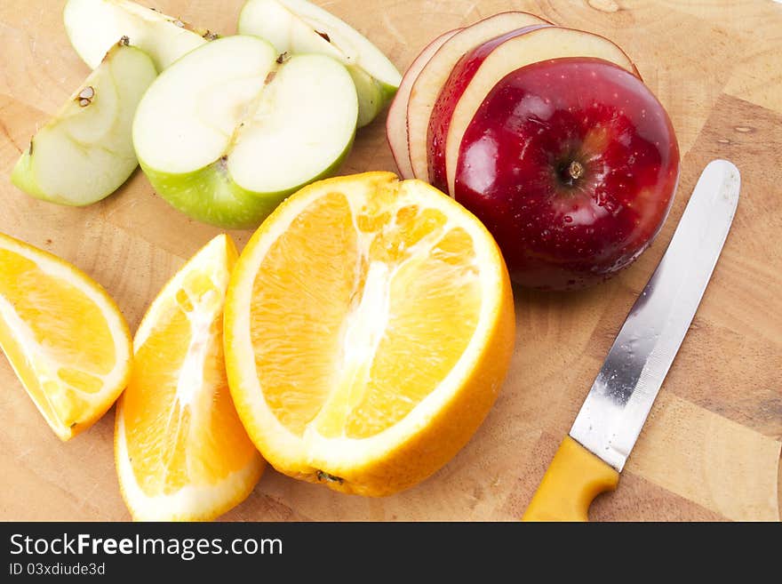 Mixed fruit on wood plate sliced and cut by yellow knife. Mixed fruit on wood plate sliced and cut by yellow knife.