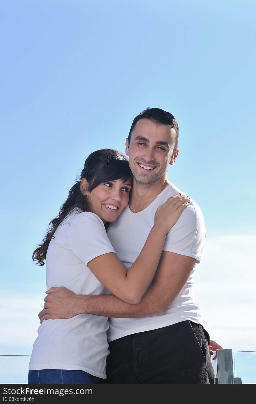 Happy young couple relax on balcony outdoor with ocean and blue sky in background. Happy young couple relax on balcony outdoor with ocean and blue sky in background