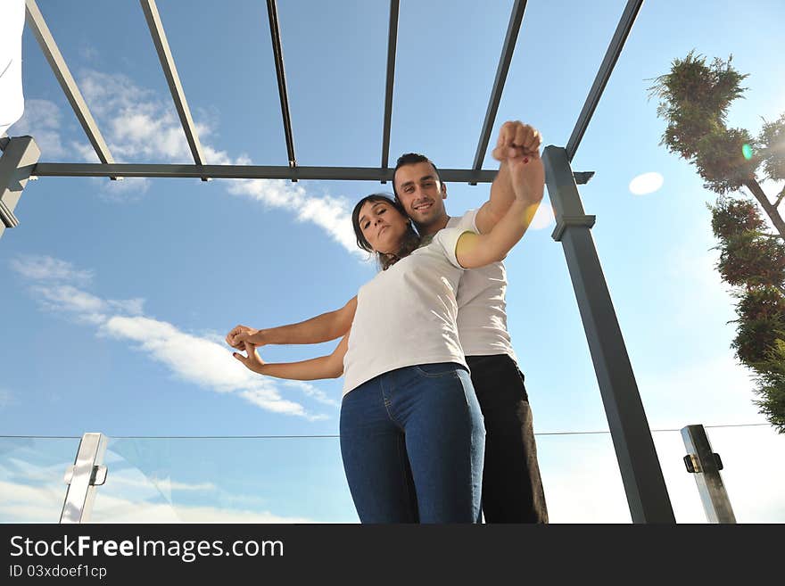 Happy young couple relax on balcony outdoor with ocean and blue sky in background. Happy young couple relax on balcony outdoor with ocean and blue sky in background