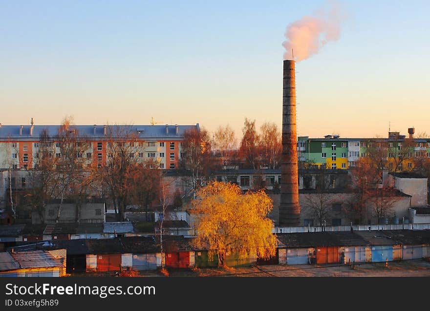 Houses And Pipe With Smoke On A Sunset