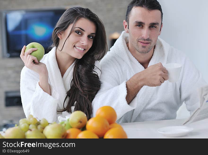 Happy couple reading the newspaper in the kitchen