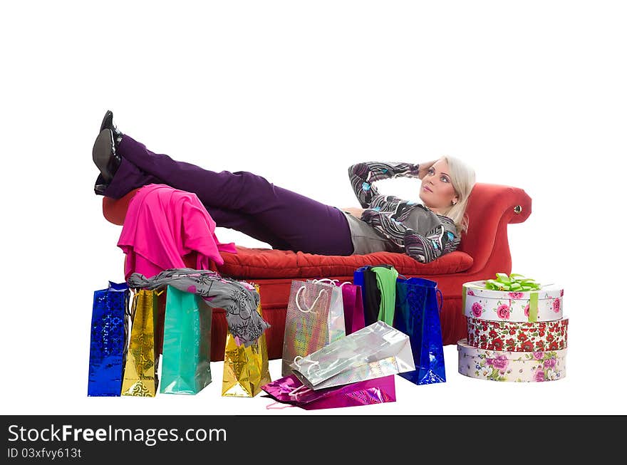 Tired woman lying on a red couch, around the shopping bags in packaging, isolated on white background. Tired woman lying on a red couch, around the shopping bags in packaging, isolated on white background