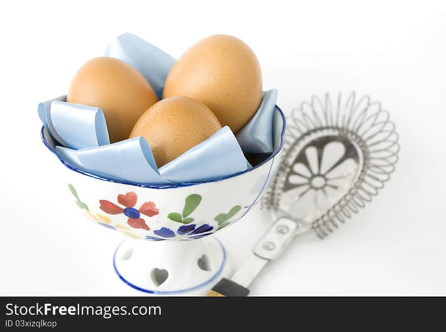 Eggs in bowl with kitchenware on white background