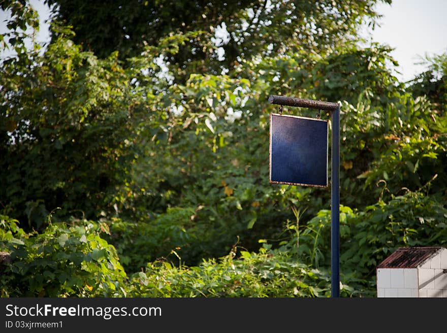 Blue  iron board hanging on pole , trees using as background. Blue  iron board hanging on pole , trees using as background