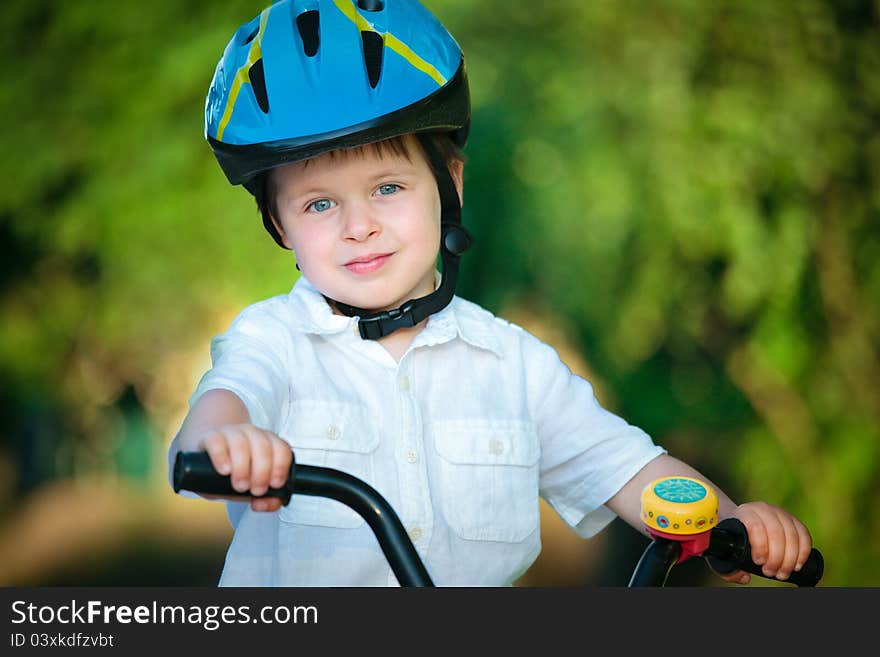 Happy boy on a bicycle in a summer park.