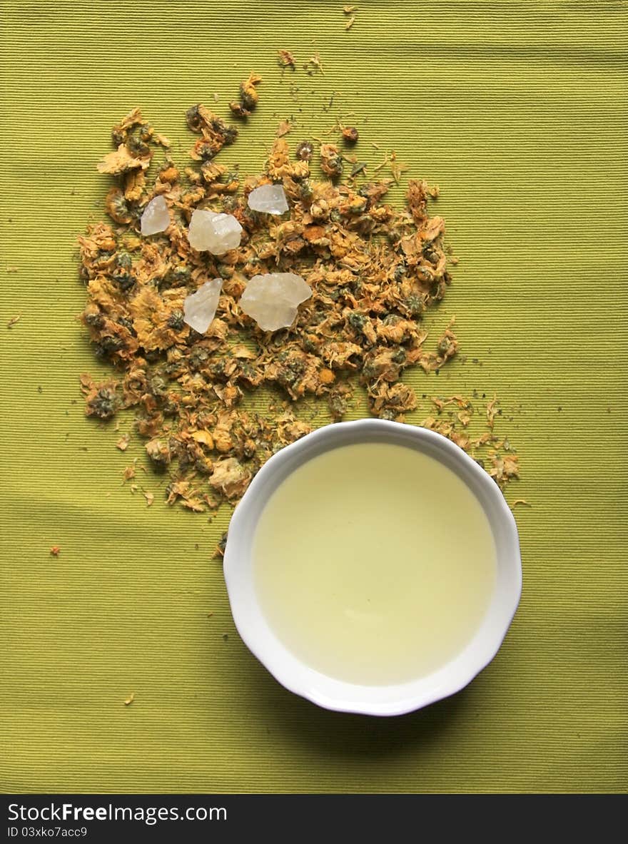 A bowl of flower tea ,white sugar with green background.