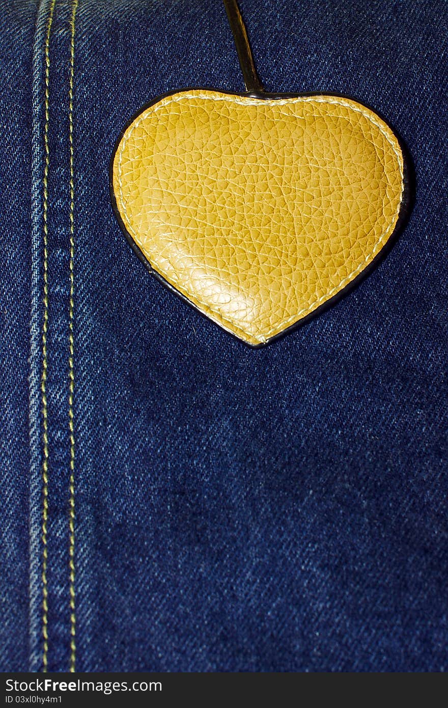 Brown leather heart on blue jeans background