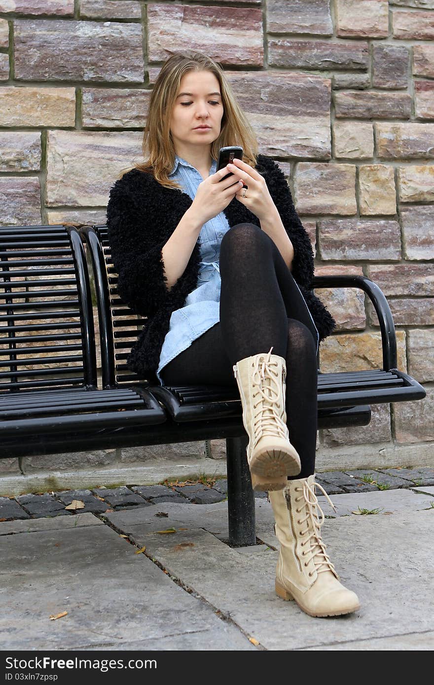 Young woman sitting at the park checking her messages. Young woman sitting at the park checking her messages