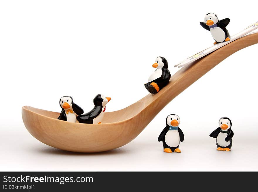 Happy penguins playing on a wooden spoon on white background