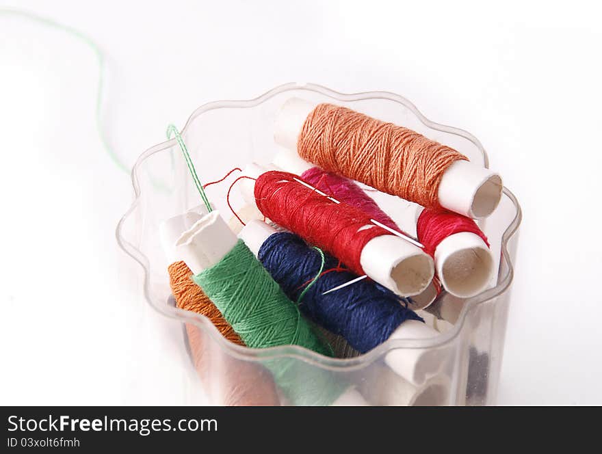 Sewing threads of different colors and a needle.