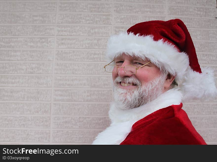 Smiling Santa in front of a white brick wall. Smiling Santa in front of a white brick wall.