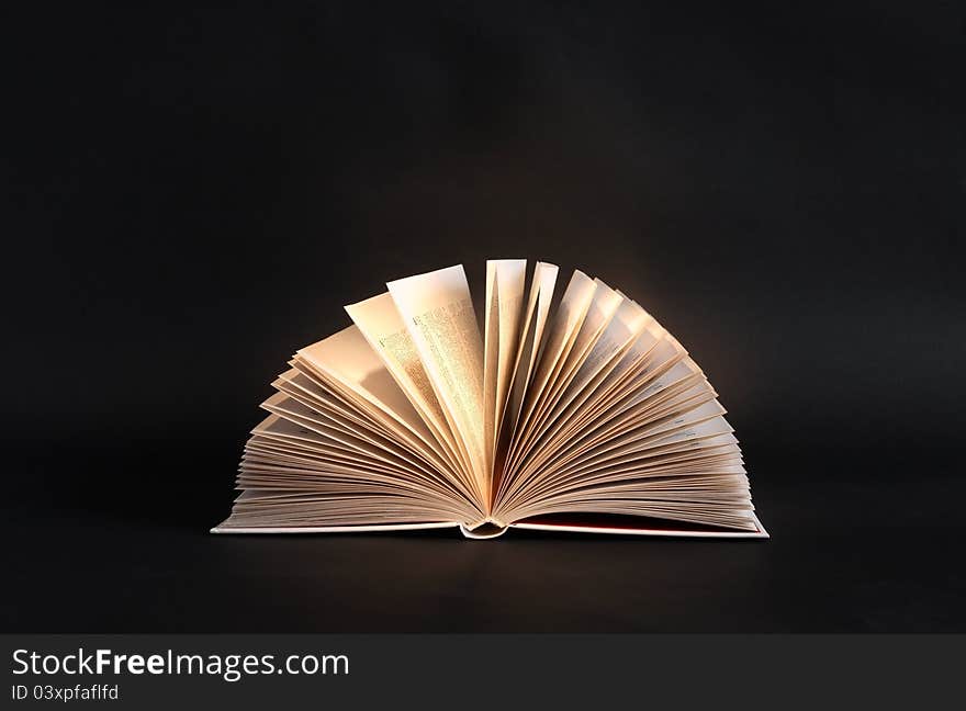 Open book under beam of light on dark background. Open book under beam of light on dark background