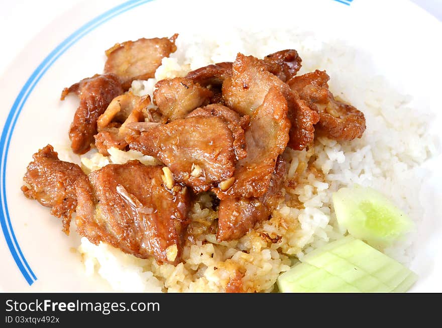 Fried pork with garlic and pepper on rice , served with fresh cucumber. Fried pork with garlic and pepper on rice , served with fresh cucumber