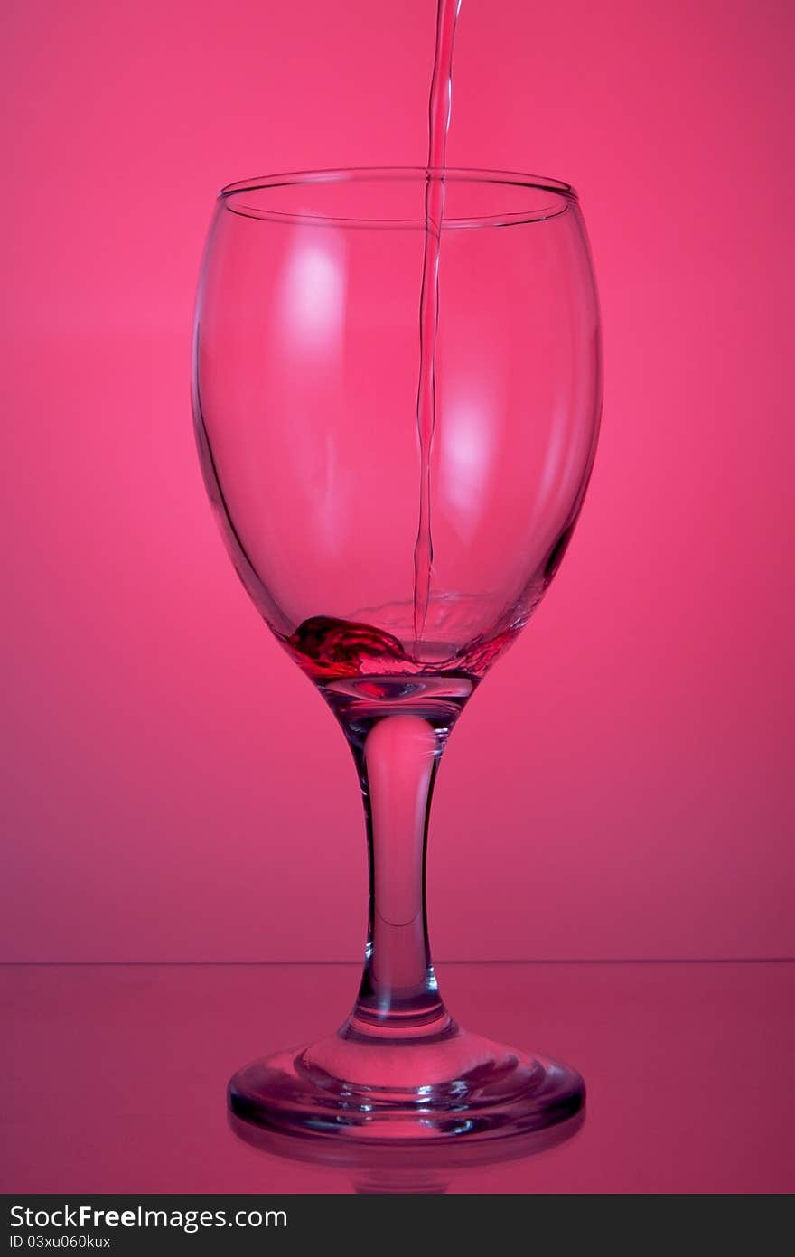 Pouring wine into a glass on a pink background. Pouring wine into a glass on a pink background.