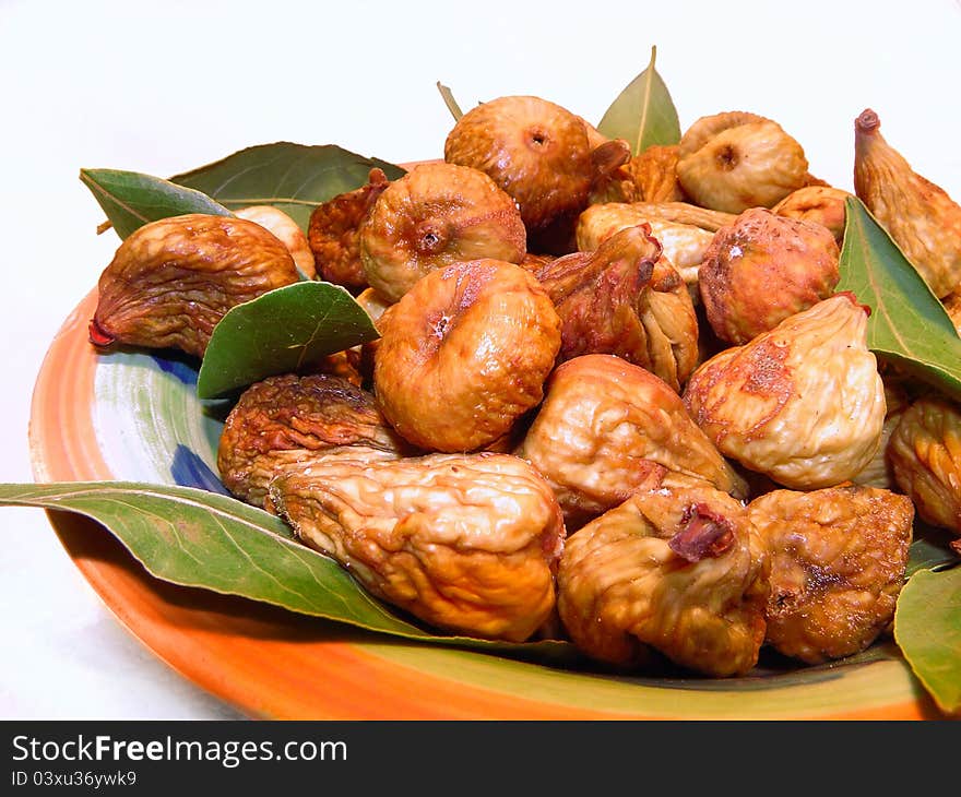 Dried figs with dry laurel leaves in a bowl.