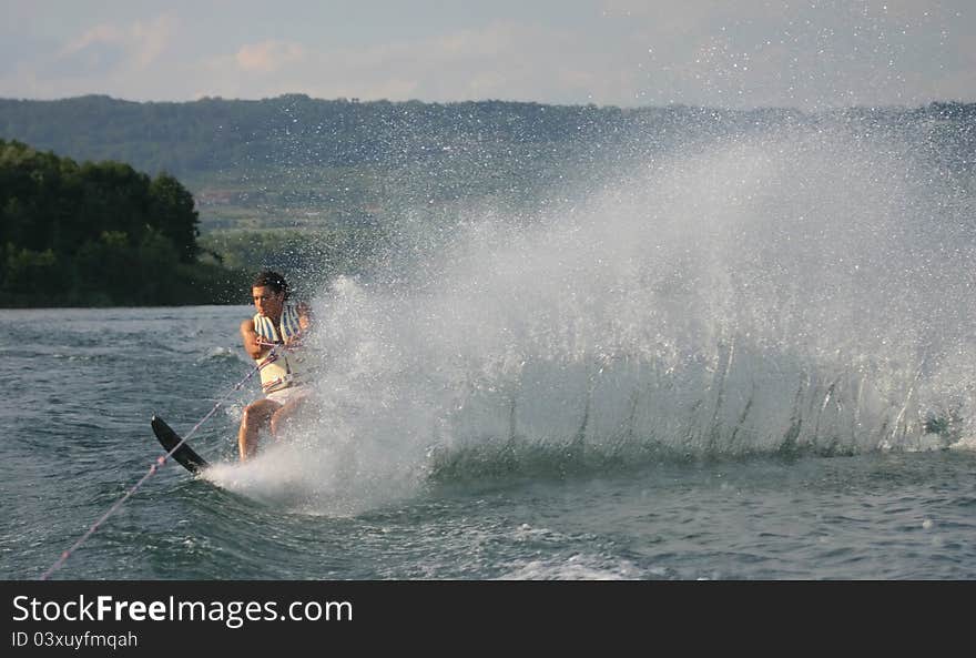 Young man is skiing with a mono and raising a wall of water. Young man is skiing with a mono and raising a wall of water