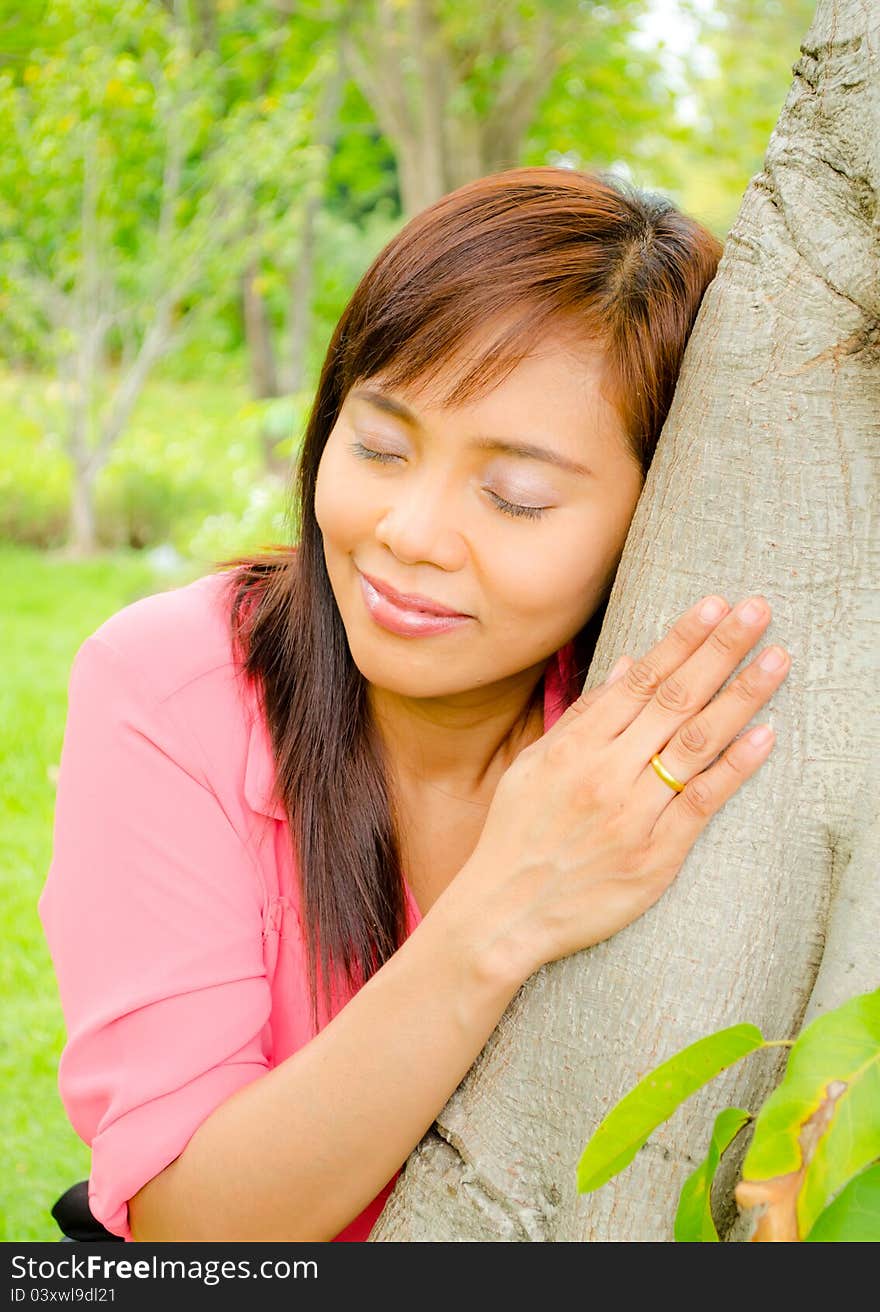 Asian girl close her eyes and listen sound from a tree in park