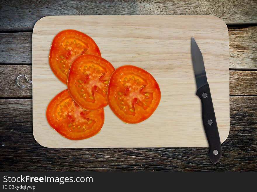 Sliced tomato and knife on chopping board. Sliced tomato and knife on chopping board