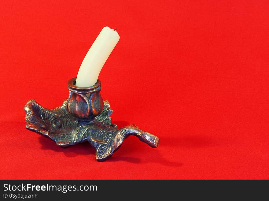 Extinguished the candle in a metal candlestick with a red background. Extinguished the candle in a metal candlestick with a red background