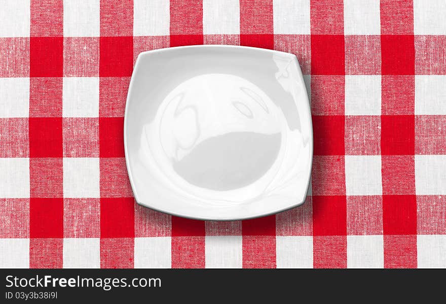 White square plate on red checked fabric tablecloth