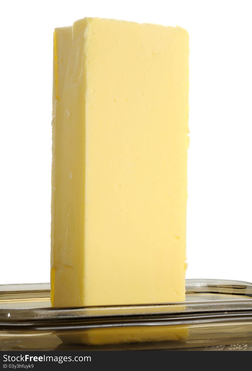 A stick of butter on a glass butterdish against a white background. A stick of butter on a glass butterdish against a white background