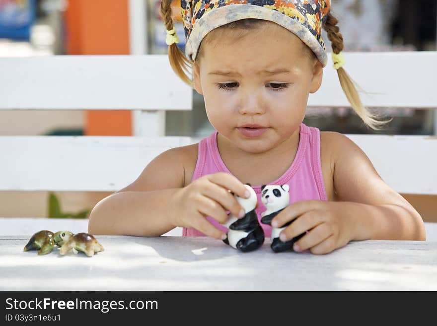 A girl playing with toy pandas at the table