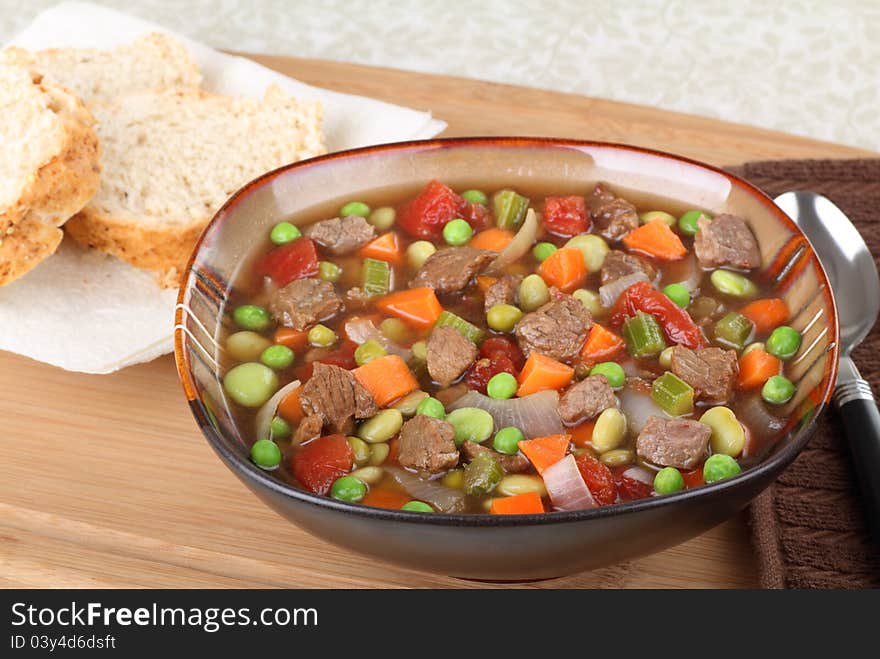 Vegetable beef soup in a bowl with bread on the side. Vegetable beef soup in a bowl with bread on the side