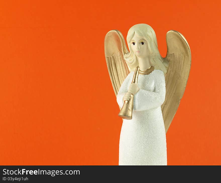 Christmas angel with a trumpet on orange background