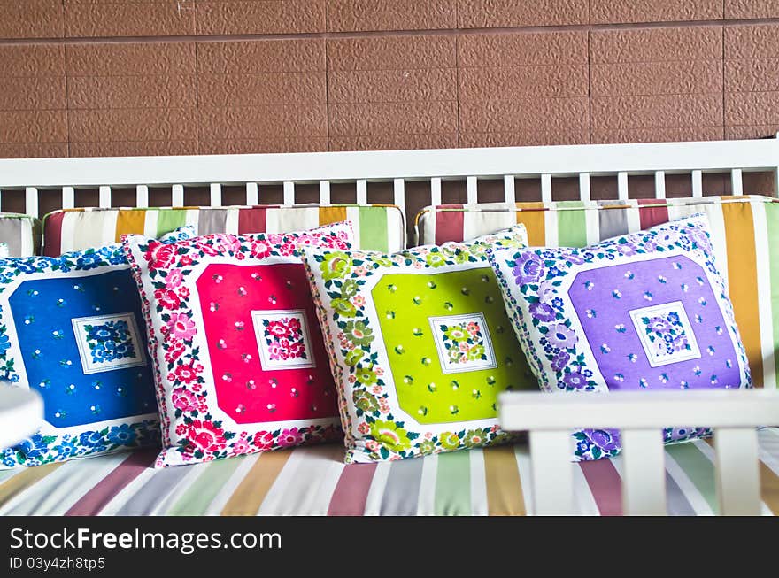 Colorful pillows with brown brick wall show texture and pattern