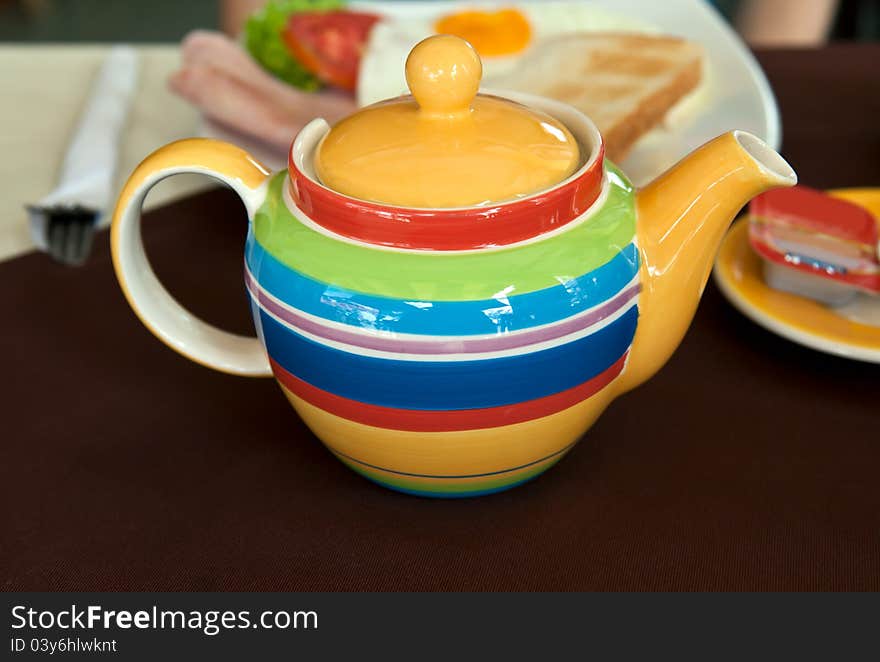 Colored striped teapot on the table with breakfast