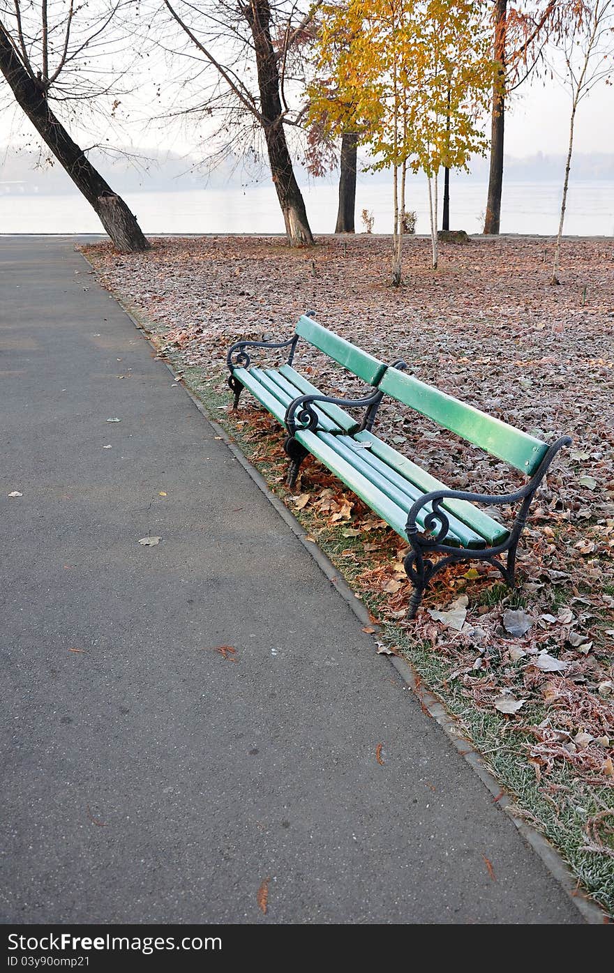 Bench on alley in a park at autumn morning