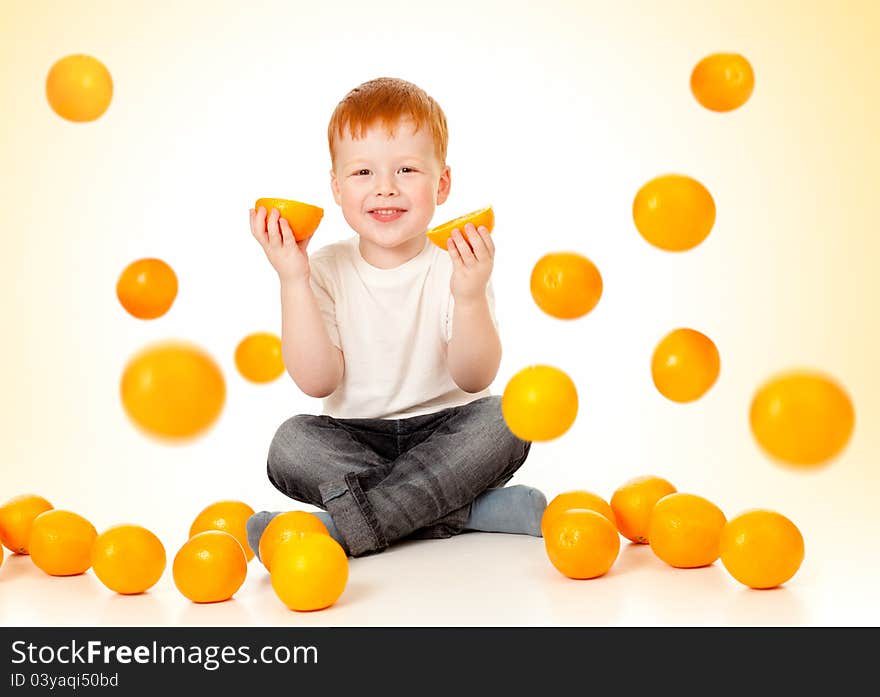 Redheaded boy in studio with falling oranges and oranges in his hands. Redheaded boy in studio with falling oranges and oranges in his hands