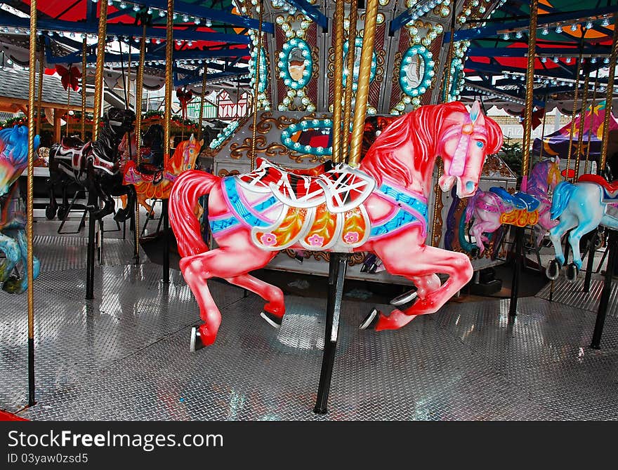 Pink carousel horse on colorful merry-go-round