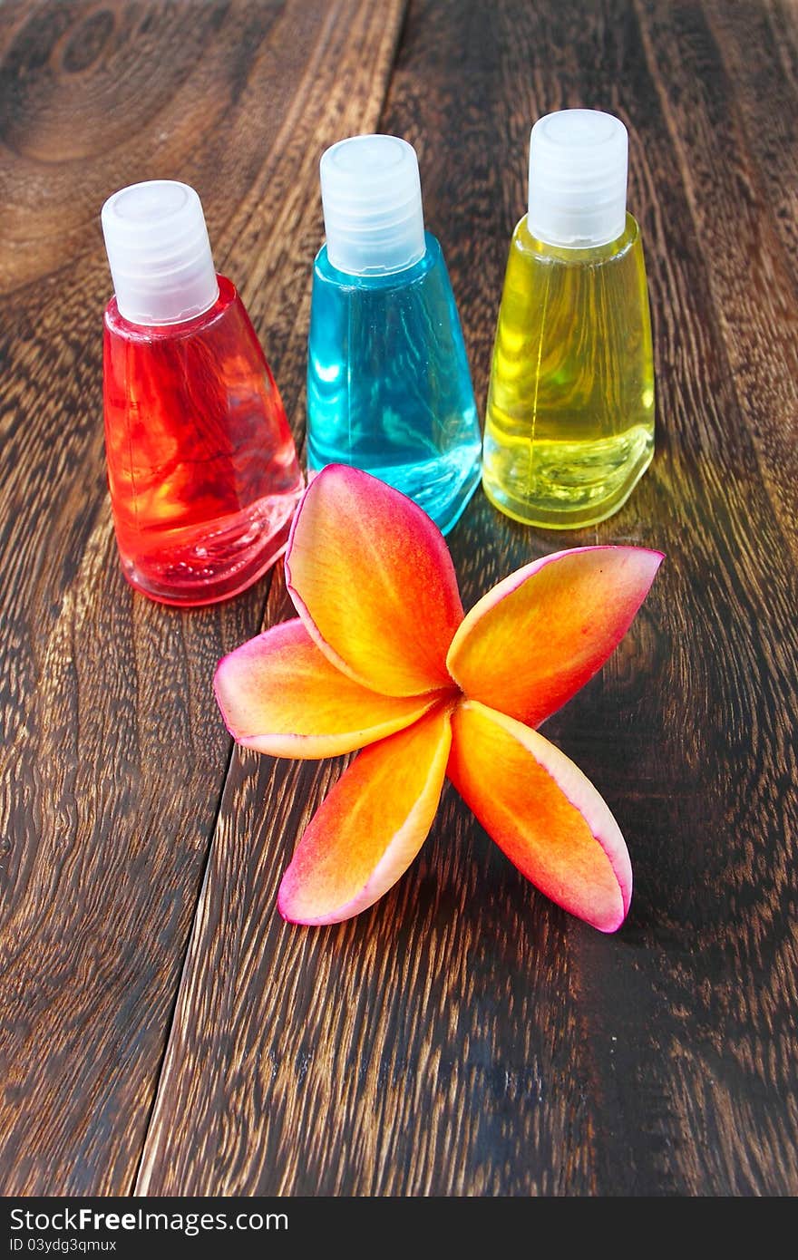 Toiletries and plumeria flower on wood floor