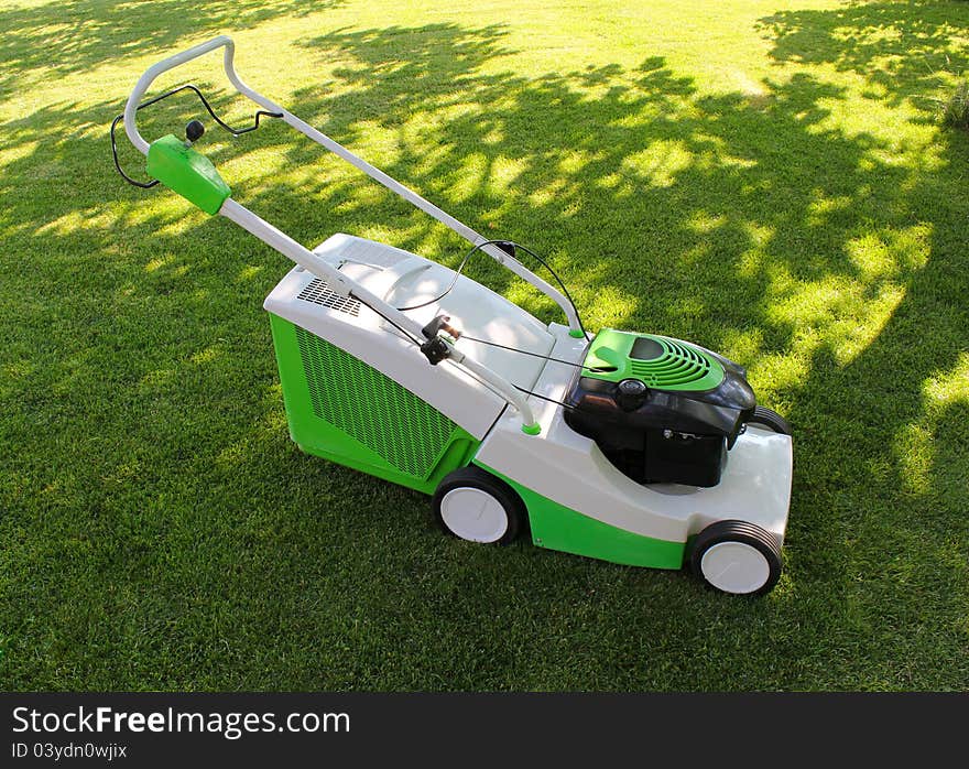 Green lawn mower on the green lawn. Green lawn mower on the green lawn