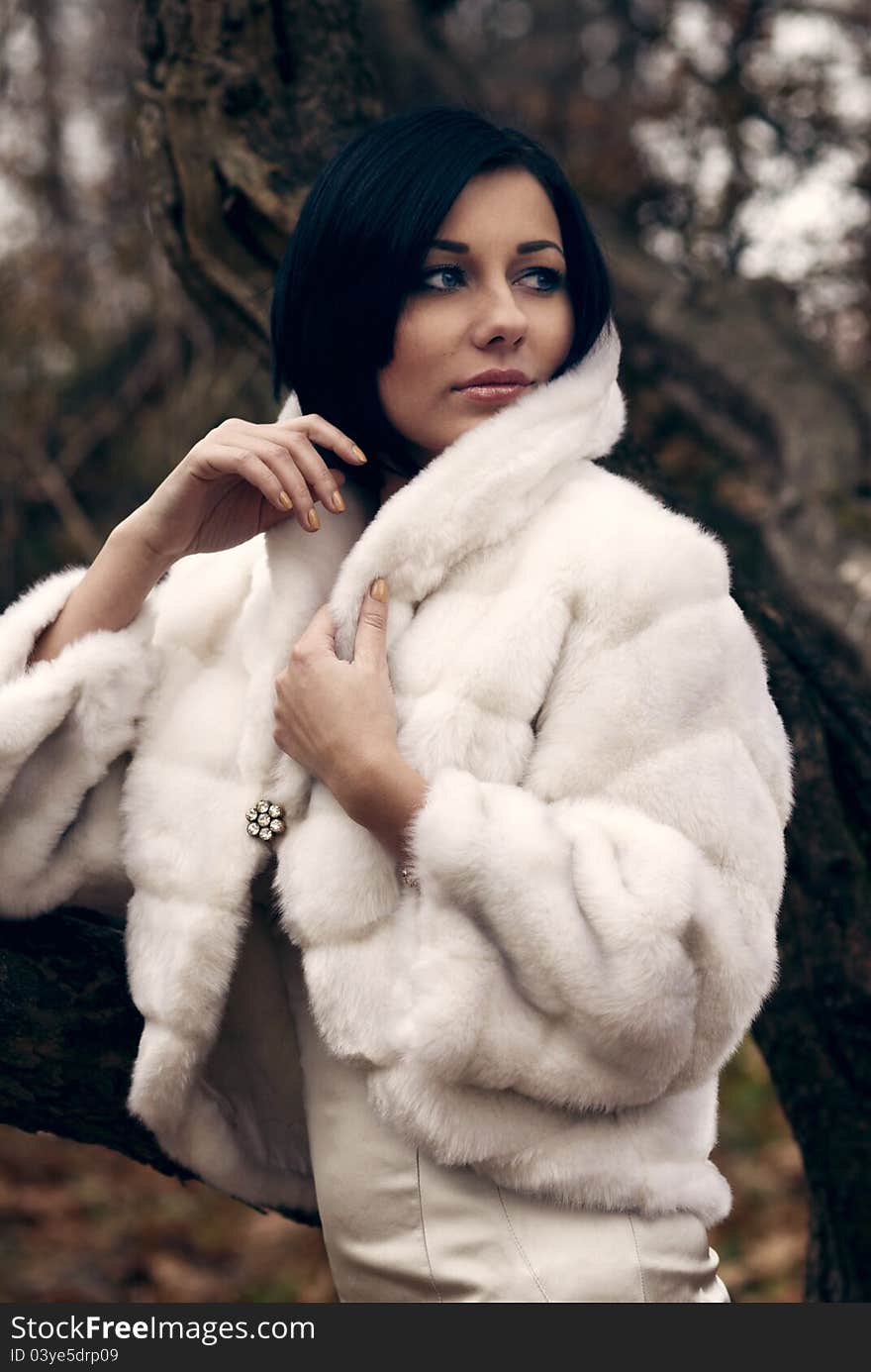 Elegant girl with black hair in white coat with high collar. Elegant girl with black hair in white coat with high collar